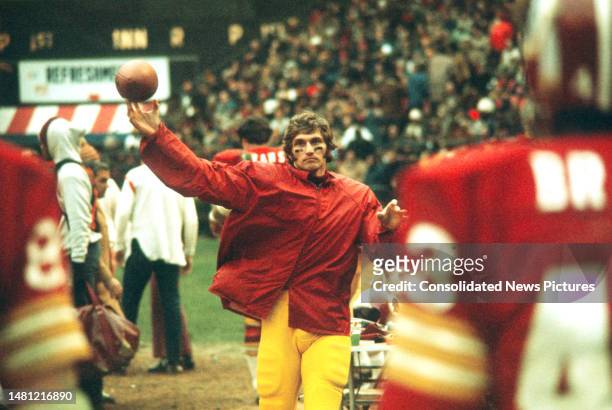 View of American football player Joe Theismann , quarterback for the Washington Redskins, as he warms-up on the sidelines during a game at RFK...