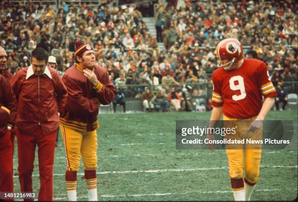 American football coach George Allen , of the Washington Redskins, walks with his team's quarterbacks Bill Kilmer and Sonny Jurgensen during a game...