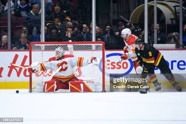 Jacob Markstrom of the Calgary Flames makes a save on J.T. Miller of the Vancouver Canucks as Jonathan Huberdeau of the Calgary Flames defends in...