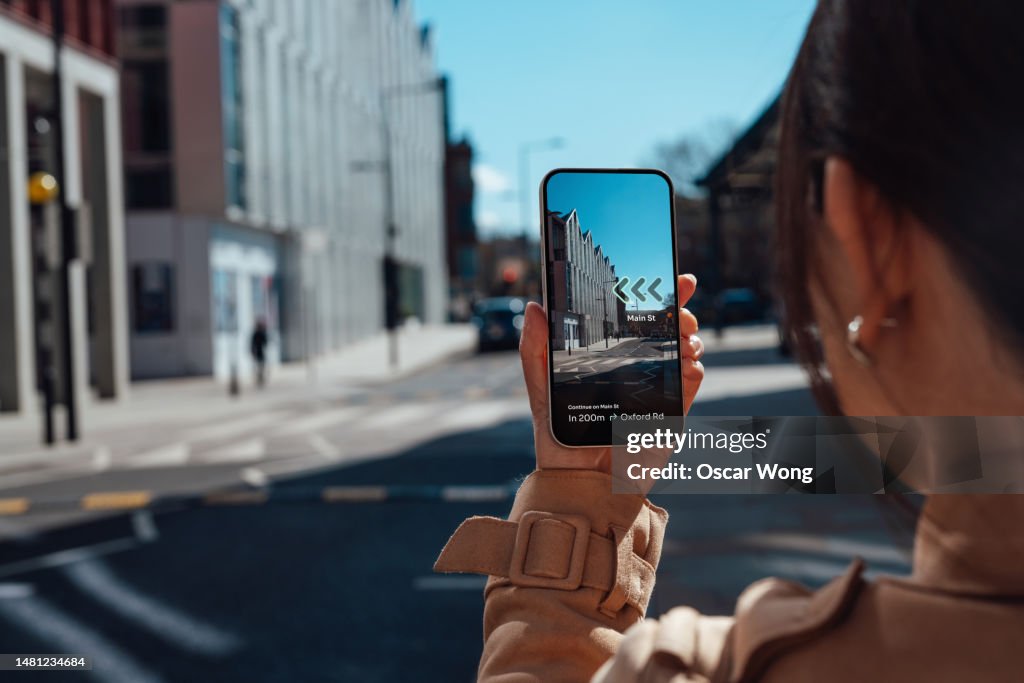 Young woman finding direction in the city with augmented reality on smartphone