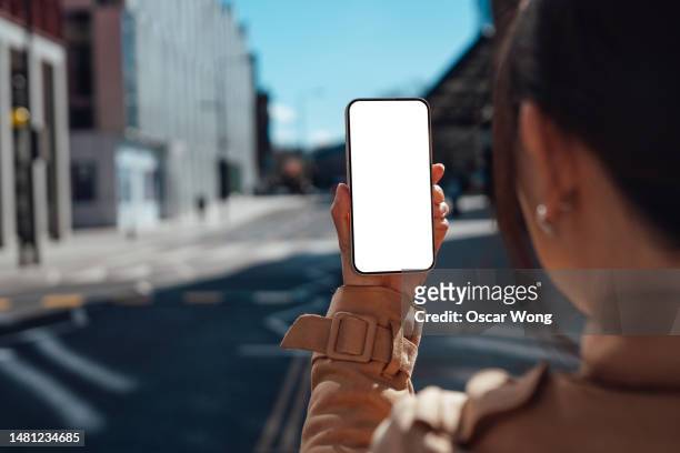 young woman using smartphone on city street - femme de dos smartphone photos et images de collection