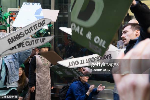 Man pulls apart pieces of a giant prop credit card that has just been cut up by giant prop scissors, at climate rally and protest outside a JP Morgan...
