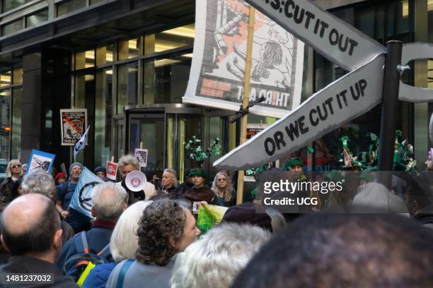 Reverend Billy, using a bullhorn, addresses dozens of climate activists, during Stop Dirty Banks NYC day of action, outside a revolving door entrance...