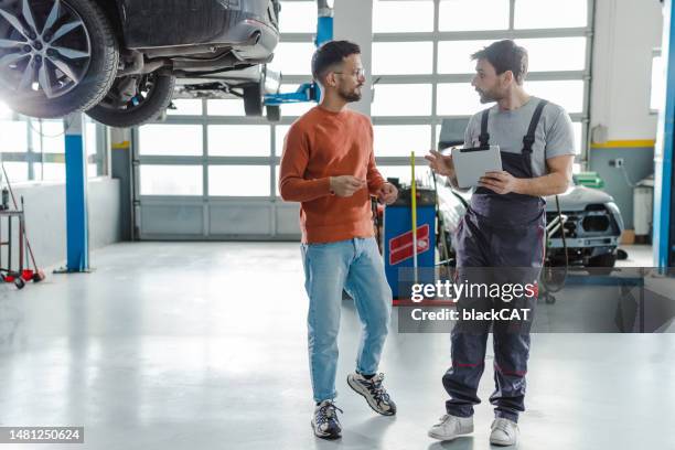 kunde und kfz-techniker im gespräch in einer werkstatt - reparaturwerkstatt stock-fotos und bilder