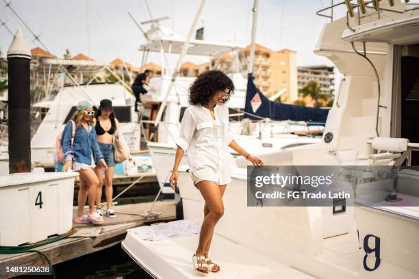 friends arriving to the harbor and entering on a yacht - yachting stockfoto's en -beelden