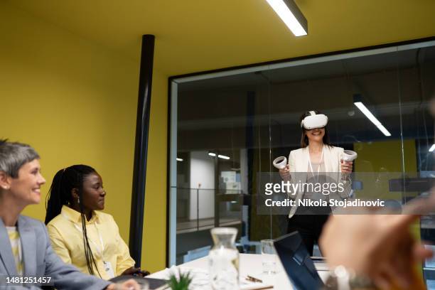 a woman shows a plan and uses vr glasses in a meeting - virtual reality simulator presentation stockfoto's en -beelden
