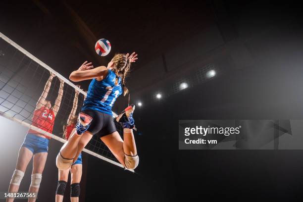 volleyballspielerinnen kicken den ball durch das netz - volleyball stock-fotos und bilder