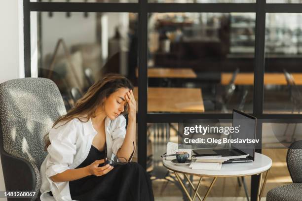 tired business woman with headache. burnout in work. working in cafe - stress stock-fotos und bilder