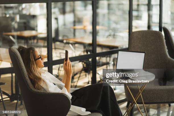 woman resting and wasting time in phone on social media. coffee break on workplace in cafe - perder el tiempo fotografías e imágenes de stock