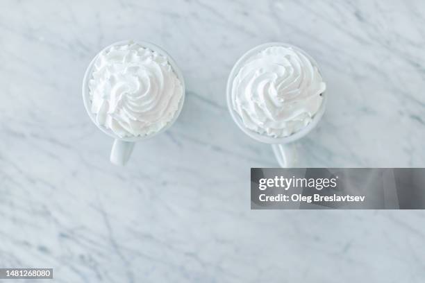 two cappuccino with cream on top. white marble table background - coffee drink white background stock pictures, royalty-free photos & images