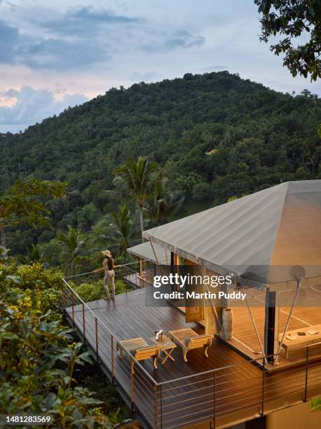 female tourist admiring sea view while standing on decking of tented villa, at eco friendly luxury glamping resort, at dawn - surat thani province stock pictures, royalty-free photos & images
