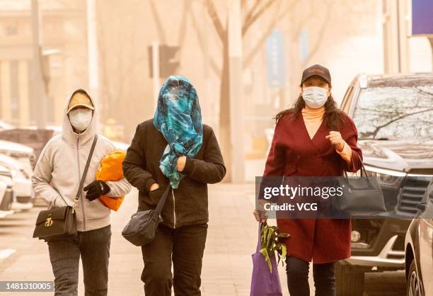 Citizens wearing masks walk at a street in a sandstorm on April 10, 2023 in Hohhot, Inner Mongolia Autonomous Region of China.
