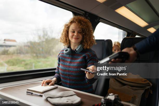 smiling woman paying for her train ticket with mobile app. - train ticket stock pictures, royalty-free photos & images