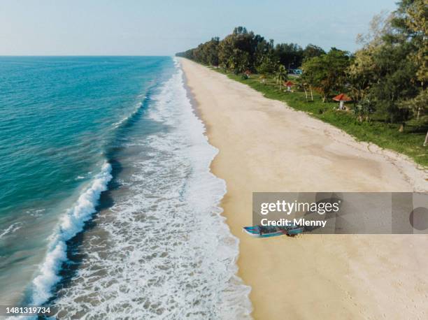 fishermen pushing long tail boat into the sea thailand thai beach phang nga - longtail boat stock pictures, royalty-free photos & images