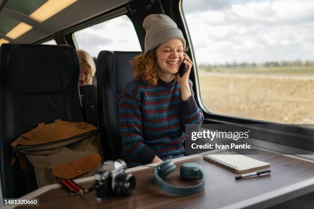 cheerful female tourist talking on cell phone in a train. - tourist talking on the phone stock pictures, royalty-free photos & images