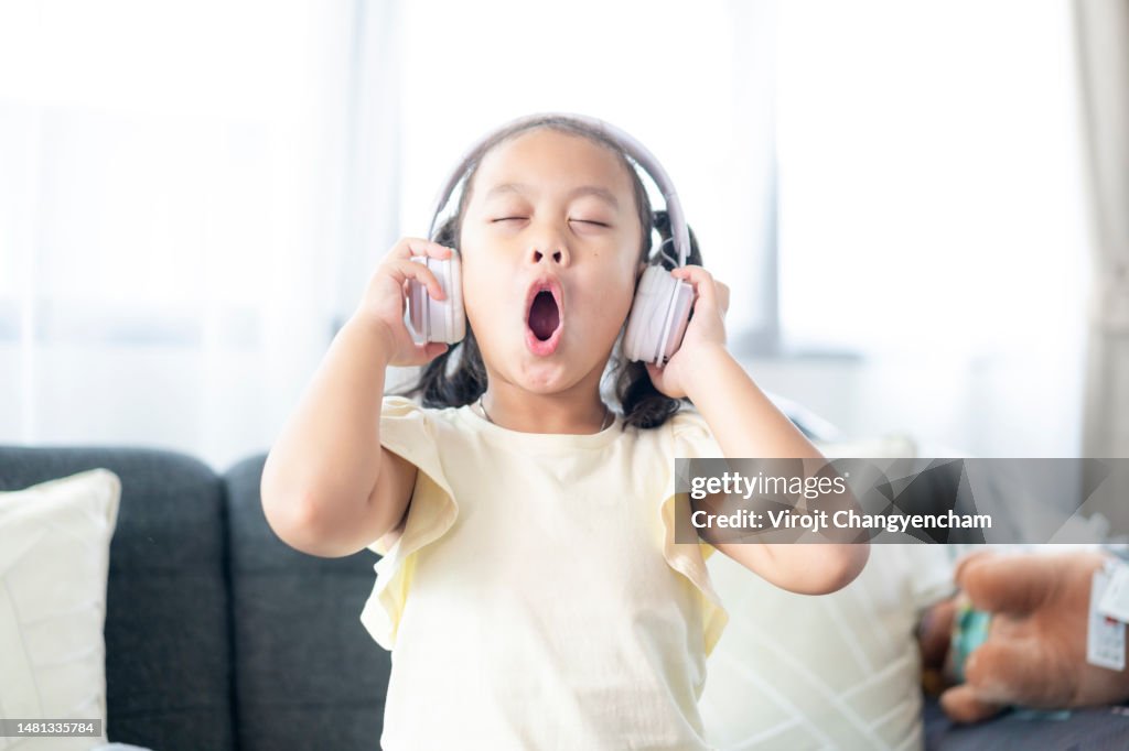 Happy Asian child girl listen to music from wireless headphone