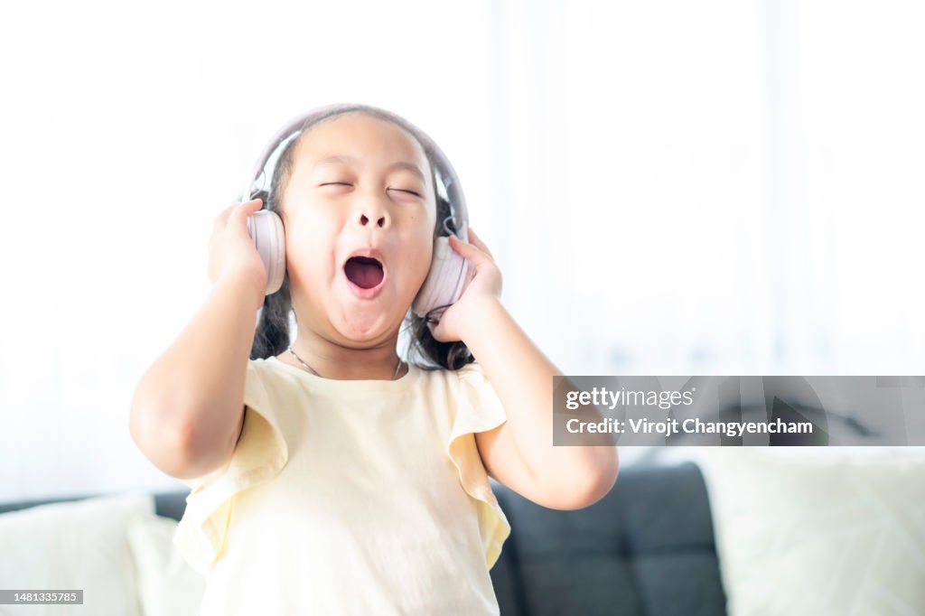 Happy Asian child girl listen to music from wireless headphone