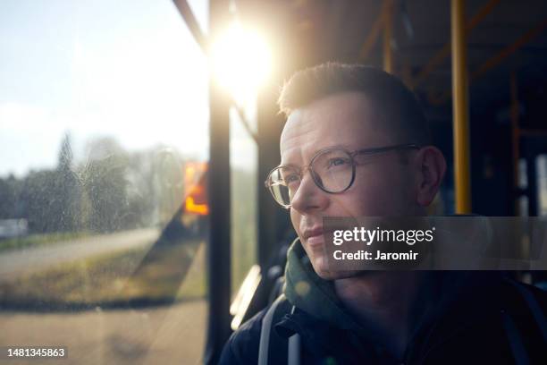 man traveling by tram and looking out of window - bus innen stock-fotos und bilder