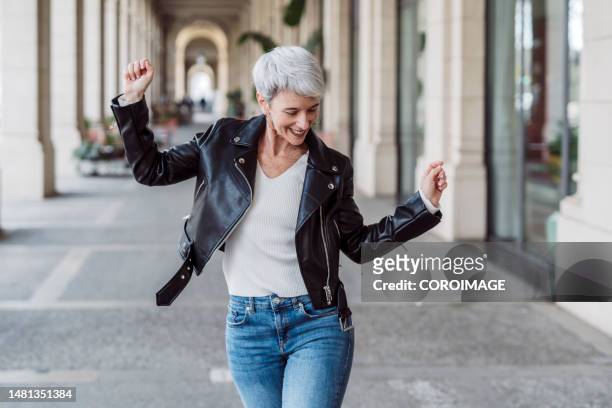 cheerful and happy mature woman dancing in the middle of the street. happiness concept. - dancing outside stock pictures, royalty-free photos & images