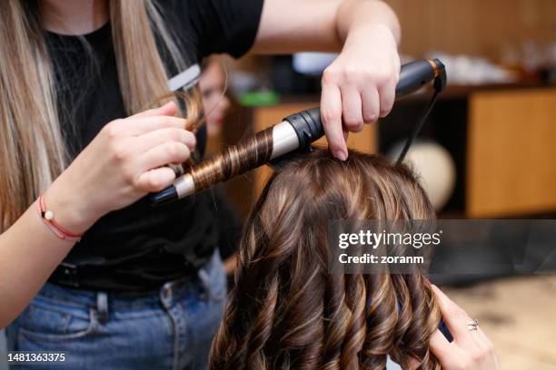 using hot curler and making curls in hair salon - hair coils stockfoto's en -beelden