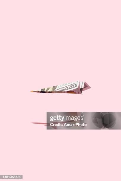 flugzeug, das dollargeld auf rosa hintergrund fliegt - origami stock-fotos und bilder