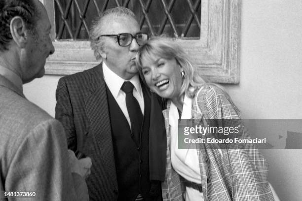 The Italian film director Federico Fellini is having fun with his actress friend Barbara Bouchet who smiles at him amused, Rome, May 07, 1984. .