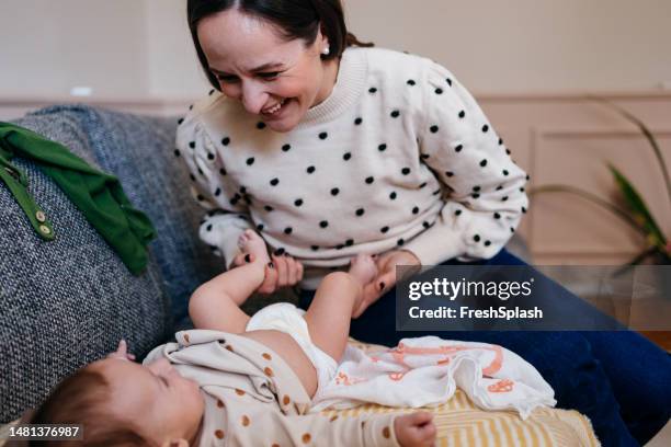 una bella donna felice che si prende cura del suo bambino carino che la sta guardando - adult baby boy diaper change foto e immagini stock