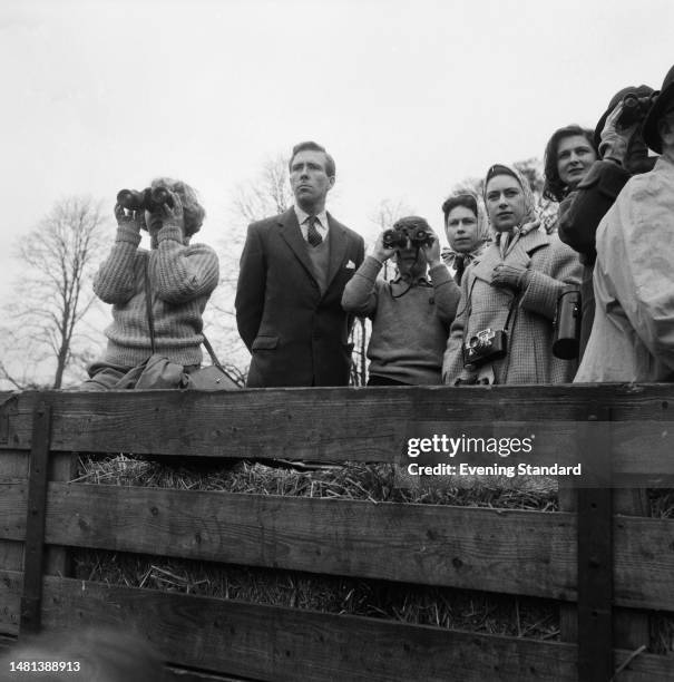 Antony Armstrong-Jones standing between Princess Anne and Prince Charles, both looking through binoculars, with Queen Elizabeth II behind and...