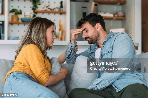 pareja preocupada hablando juntos en la sala de estar de casa. - relación humana fotografías e imágenes de stock