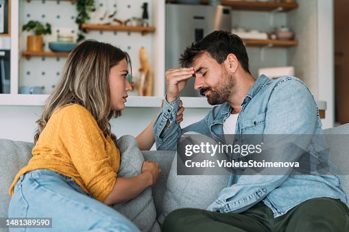 Worried couple talking together in the living room at home.