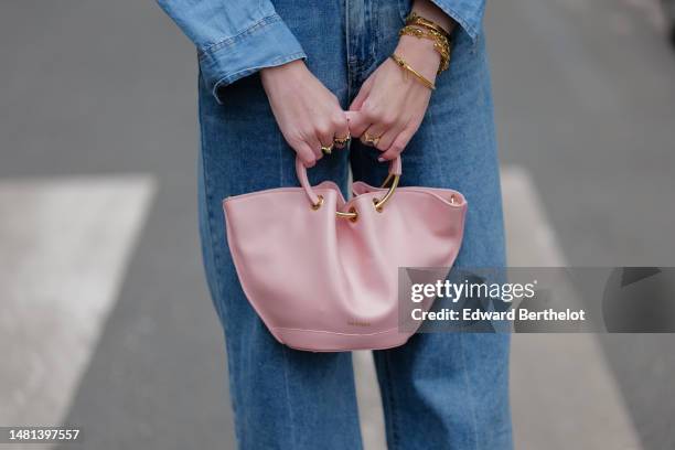 Alba Garavito Torre wears a blue denim buttoned shirt, blue denim wide ripped legs pants, gold bracelets, a pale pink matte leather handbag, during a...
