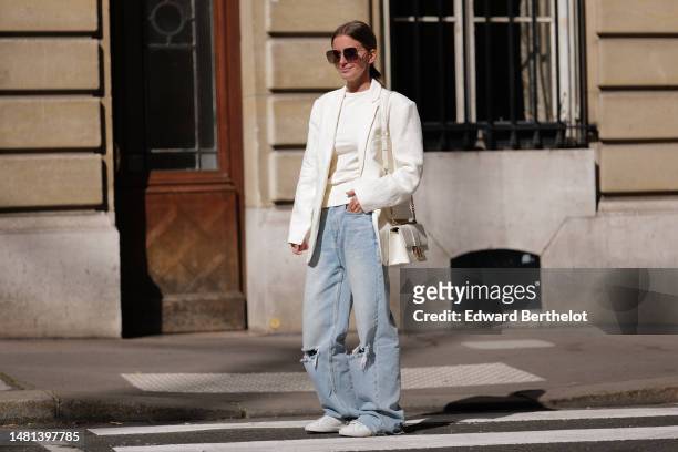 Diane Batoukina wears brown squared large sunglasses from Dior, a white t-shirt, a white linen blazer jacket from Anine Bing, a white latte matte...