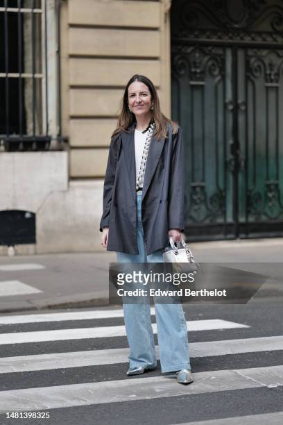 Alba Garavito Torre wears gold earrings, a white large pearls and black small pearls long necklace, a white t-shirt, a dark gray oversized blazer...