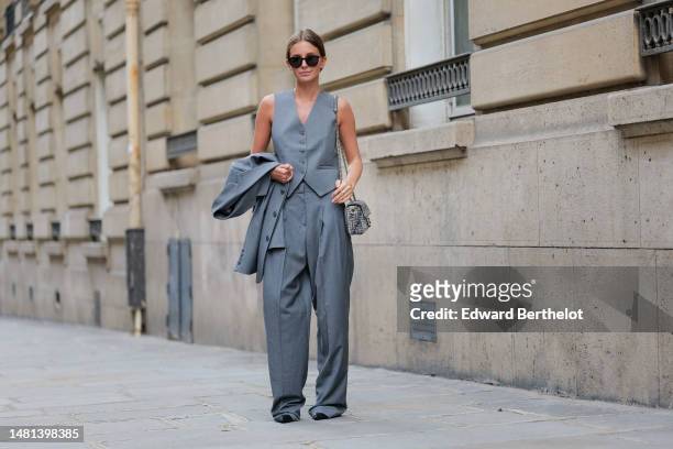 Diane Batoukina wears black sunglasses from Saint Laurent, a gray suit 3 pieces from The Frankie with a pale grau buttoned sleeveless gilet, a pale...