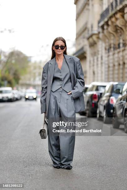 Diane Batoukina wears black sunglasses from Saint Laurent, a gray suit 3 pieces from The Frankie with a pale grau buttoned sleeveless gilet, a pale...