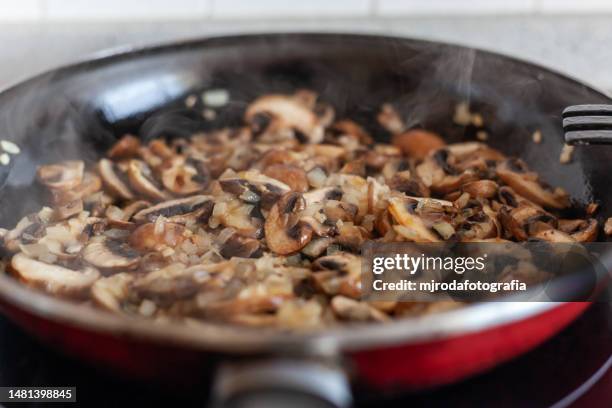 mushrooms cooking in frying pan. champignons - cooked mushrooms stock-fotos und bilder