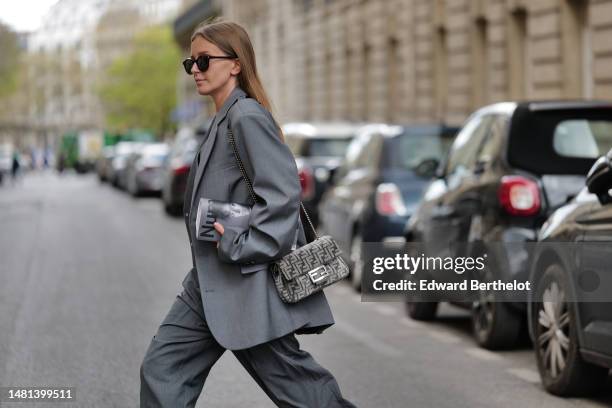 Diane Batoukina wears black sunglasses from Saint Laurent, a gray suit 3 pieces from The Frankie with a pale grau buttoned sleeveless gilet, a pale...