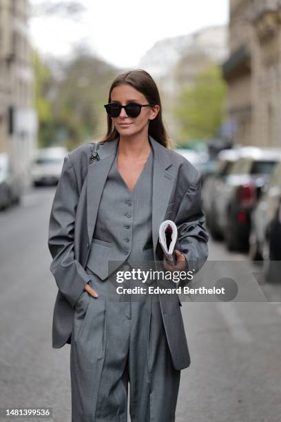 Diane Batoukina wears black sunglasses from Saint Laurent, a gray suit 3 pieces from The Frankie with a pale grau buttoned sleeveless gilet, a pale...