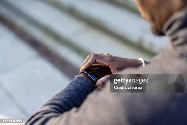 mann schaut auf seine smartwatch, während er im freien trainiert - zeitumstellung stock-fotos und bilder