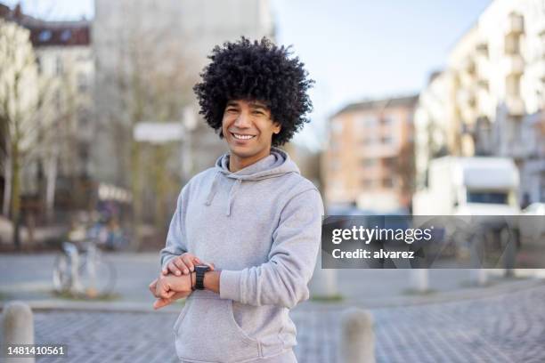 middle eastern man using smartwatch after a morning workout in the city - afro hairstyle stock pictures, royalty-free photos & images