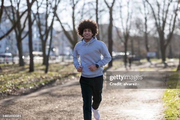 porträt eines fitten jungen mannes bei einem morgendlichen lauf im park - natural hair stock-fotos und bilder