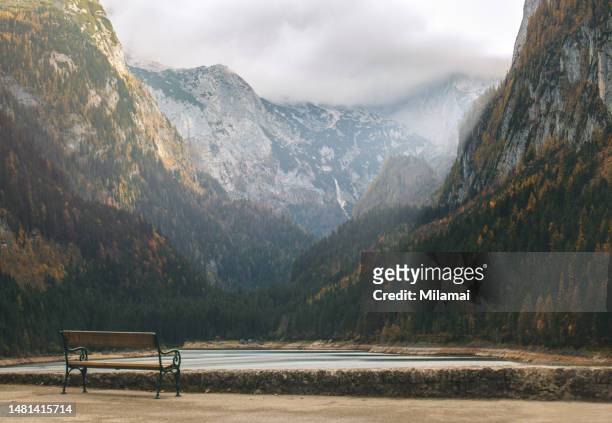 wooden empty bench in front of cloudy mountains - gmunden austria stock pictures, royalty-free photos & images