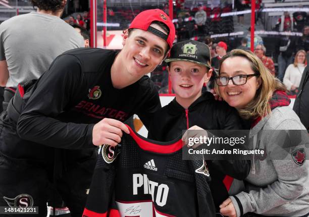 Shane Pinto of the Ottawa Senators poses for a photo after giving a fan his game-worn jersey on fan appreciations night after a 3-2 win over the...