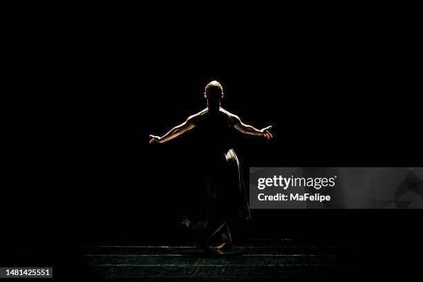 black young woman performing contemporary dance on dark stage - contemporary dance stock pictures, royalty-free photos & images