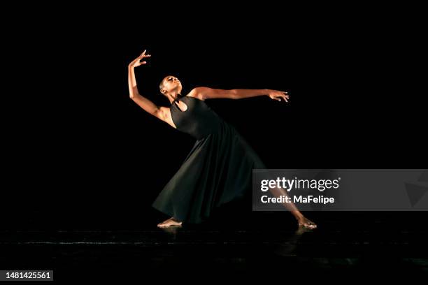 black young woman performing contemporary dance on dark stage - contemporary dance stock pictures, royalty-free photos & images