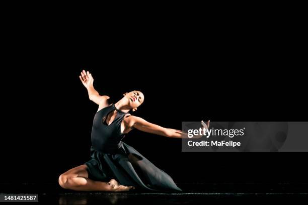 black young woman performing contemporary dance on dark stage - contemporary dance stock pictures, royalty-free photos & images