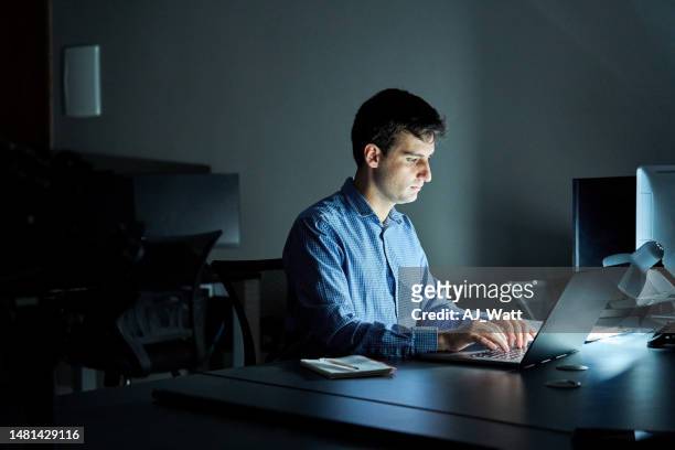 young businessman working late at night on laptop in office - laptop dark stock pictures, royalty-free photos & images