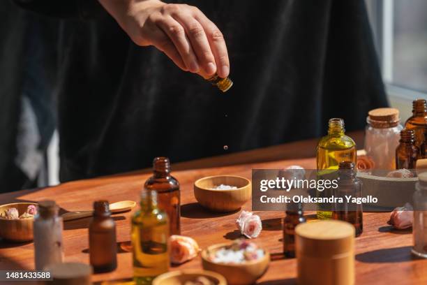 woman preparing aromatic salt on wooden table. homemade perfume from essential flower oil. skincare products, natural cosmetic. - parfumeur photos et images de collection