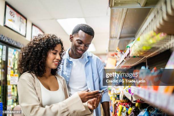 junges paar beim einkaufen in einem einzelhandelsgeschäft - supermarkt gang stock-fotos und bilder