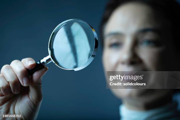 frau mit lupe - vergrößerungsglas stock-fotos und bilder